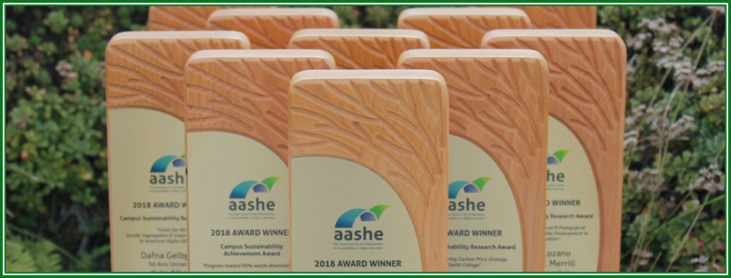 photograph of 2018 award plaques, stacked, with plants background