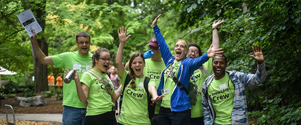 Group of people cheering about sustainability and wearing matching green shirts