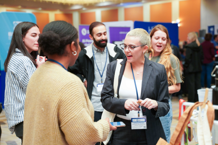 Two people talking in the foreground with other in the background.
