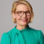 light-skinned colored woman with short blonde hair and a green top