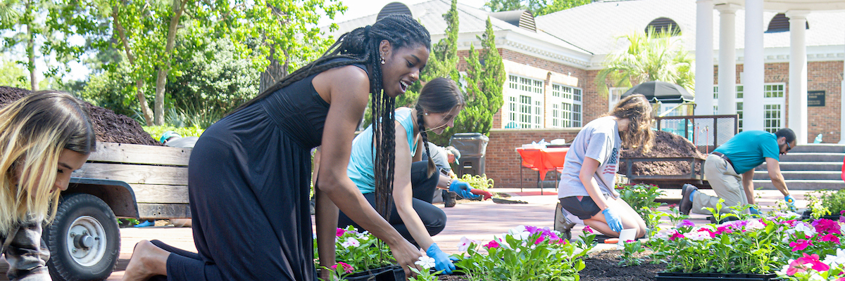 Students planting flowers in front of a building.